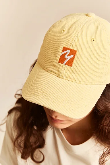 AI-generated photo of a person in a yellow corduroy cap with an embroidered logo